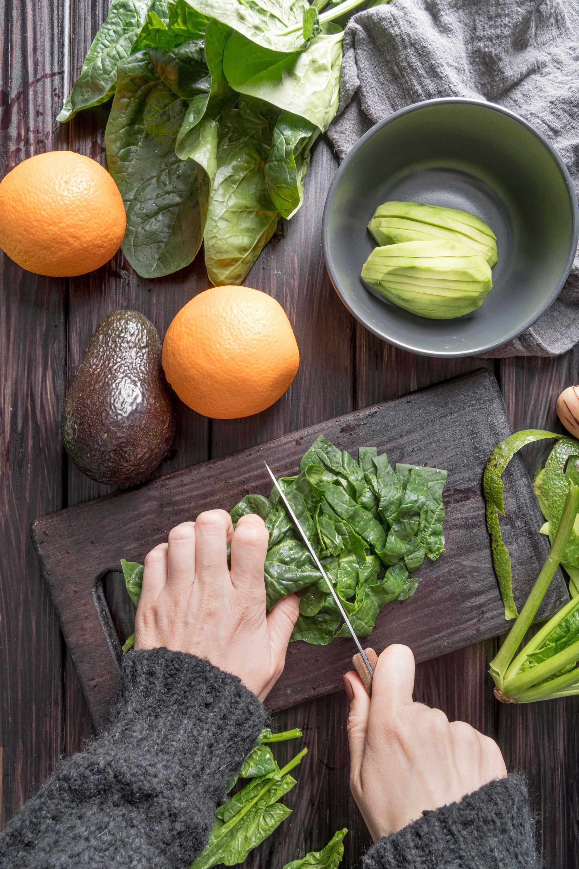 Préparation d'aliments frais, comme des épinards, oranges et avocats, pour une alimentation saine et équilibrée, inspirée des principes de la diététique chinoise