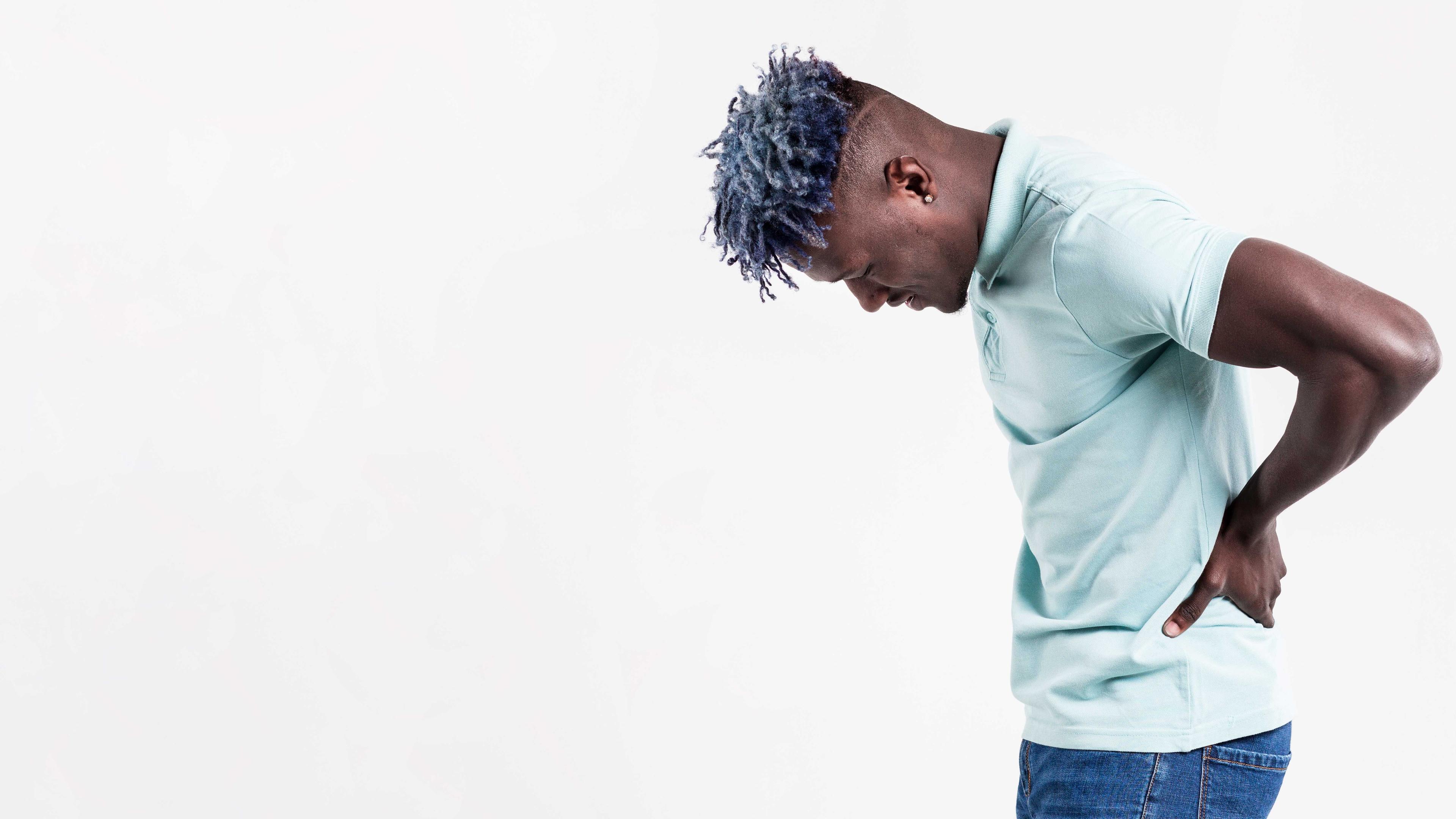 Homme se tenant le bas du dos avec une expression douloureuse, illustrant une lombalgie.